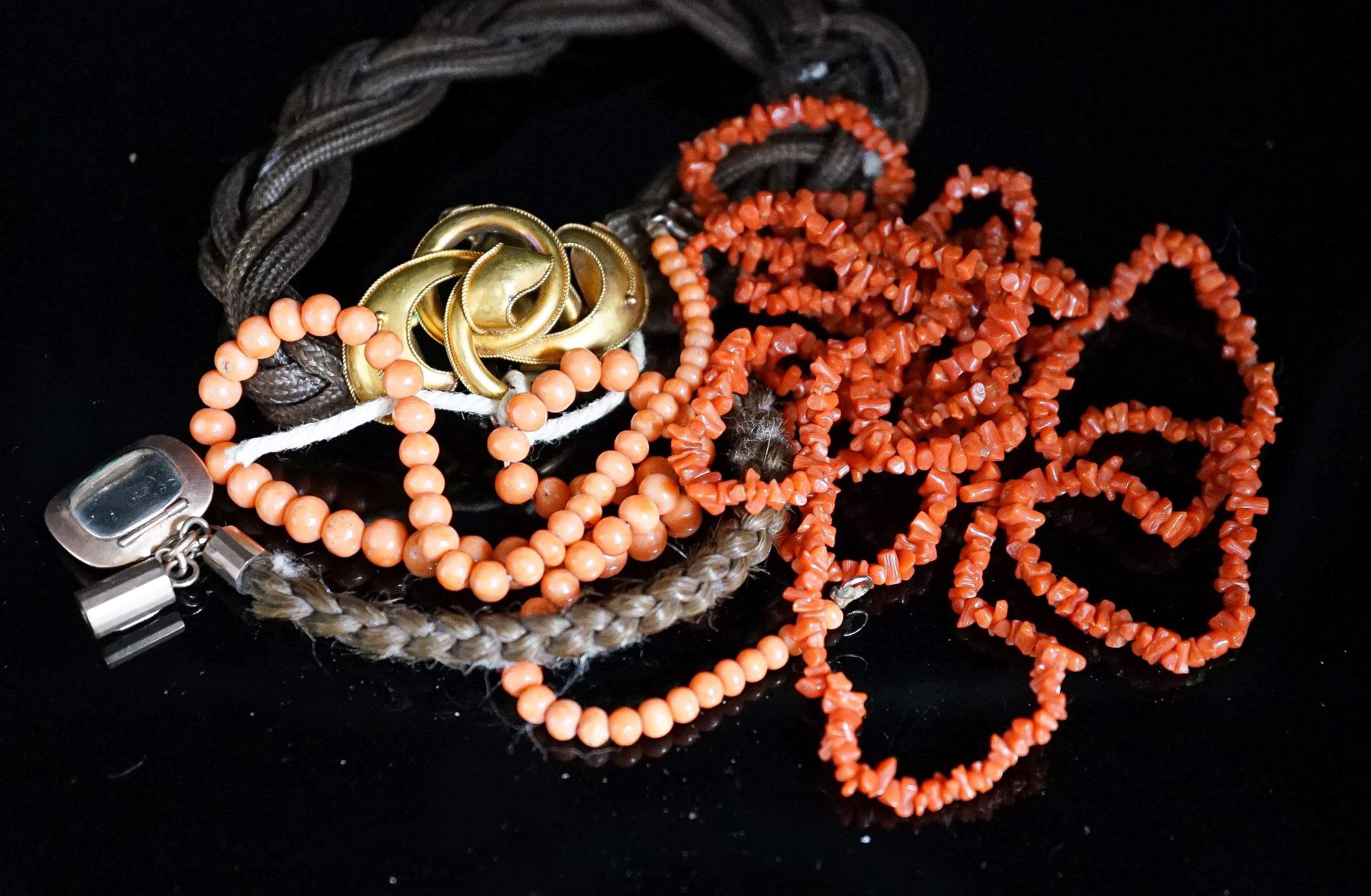 A Victorian yellow metal mounted hairwork bracelet, hung with plaited hair tassel with yellow metal fob, and two coral necklaces.